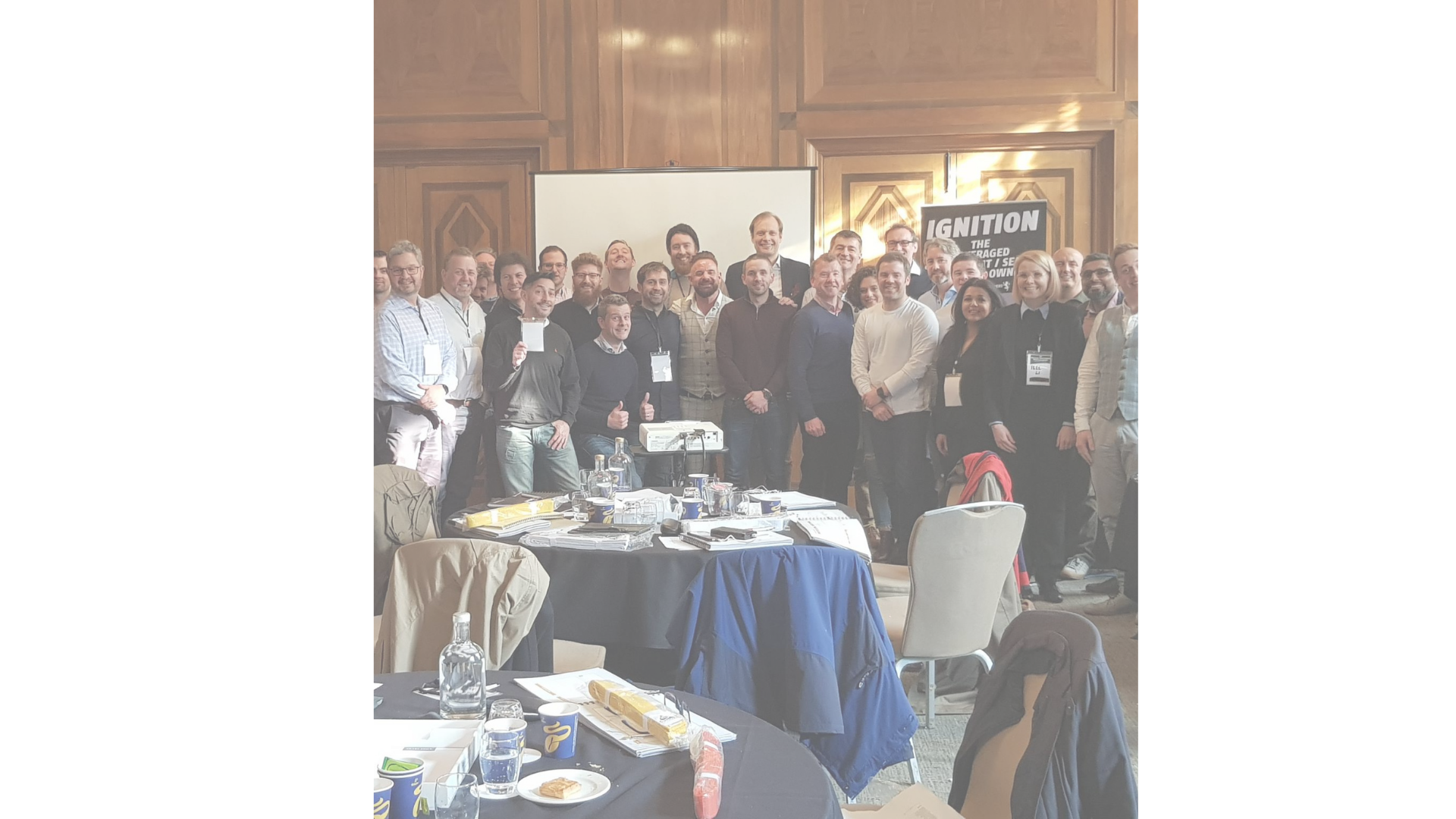 A group photo of around thirty members at a live London workshop in front of the Ignition banner